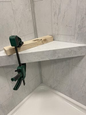Using a C-clamp to hold bench or shelf securely in place until adhesive dries
