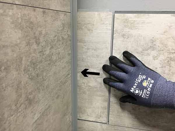 Push tile into corner trim channel until it can lay flat on the substrate